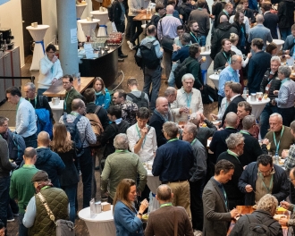 A large number of people gather in the foyer and engage in lively discussions while having a welcome coffee.