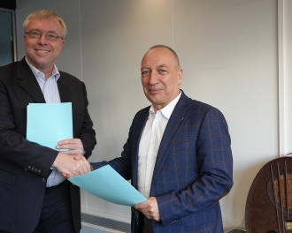 Das Foto zeigt Martin Leuthold, Managing Director a.i. von Switch, beim Händeschütteln mit Bernard Maissen, Direktor des BAKOM, nach der Vertragsunterzeichnung.