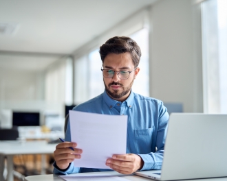 Man checking document working at laptop computer in office.