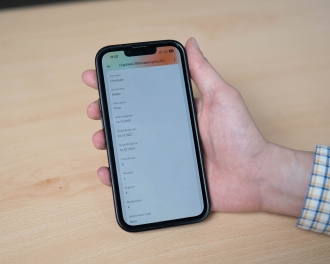 The photo shows a hand holding a smartphone which displays a digital baccalaureate certificate.