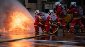 Firefighters use a water hose to suppress a fire during emergency response training.